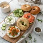 A toasted bagel with cream cheese, smoked salmon, capers, and dill, served on a rustic ceramic plate with a linen napkin.
